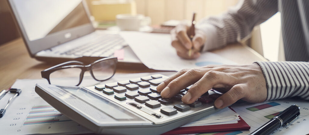 Človek pracujúci s kalkulačkou a notebookom.