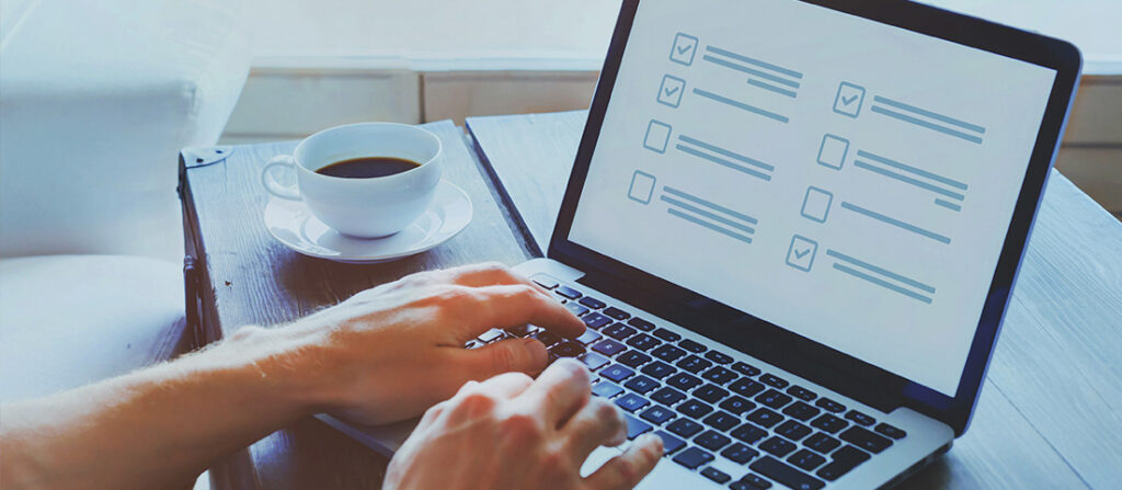 Ruky na klávesnici notebooku a šálka kávy položená vedľa.