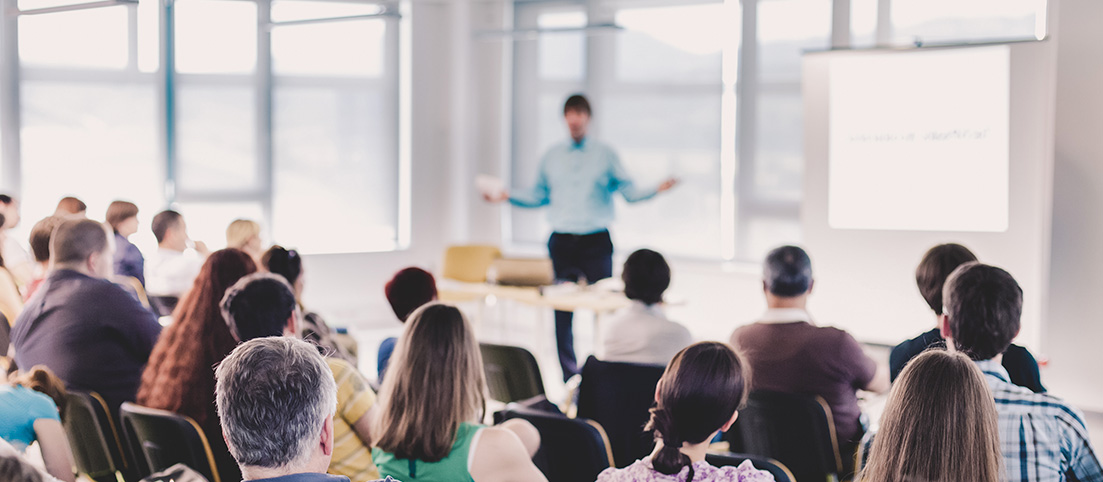 Skupina dospelých počúva prednášajúceho počas vzdelávacieho seminára v jasnej miestnosti.
