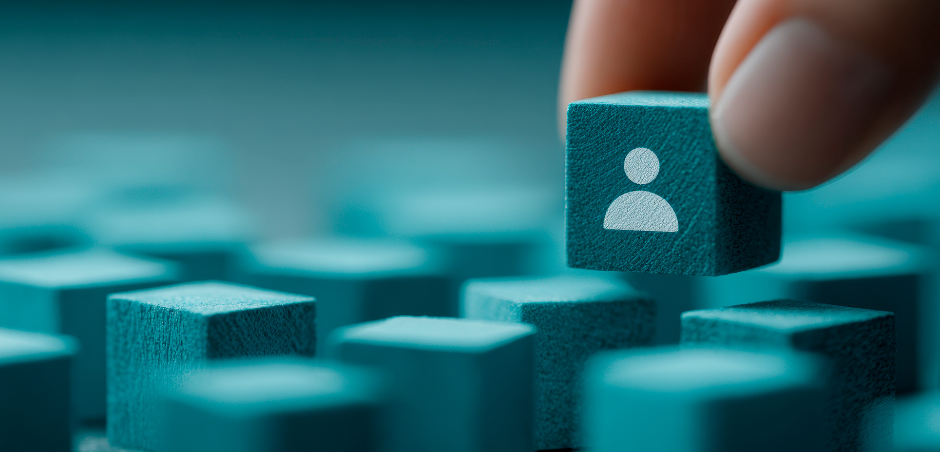 Ruka drží modrý kockový blok s ikonou osoby nad viacerými podobnými blokmi.