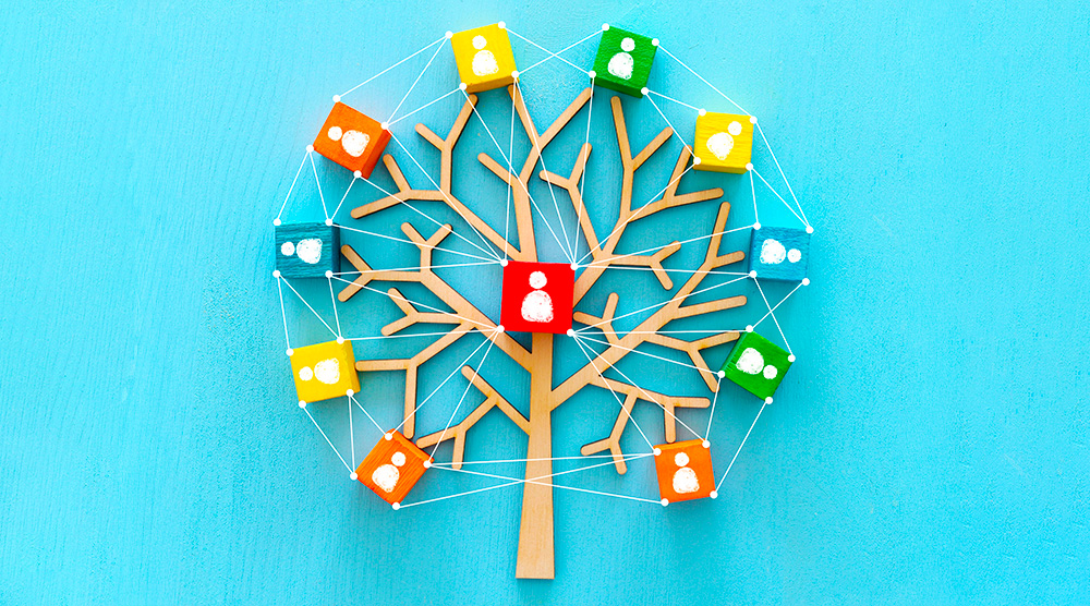 Drevený strom s farebnými kockami a ikonami ľudí znázorňujúci rodinné väzby a prepojenia.