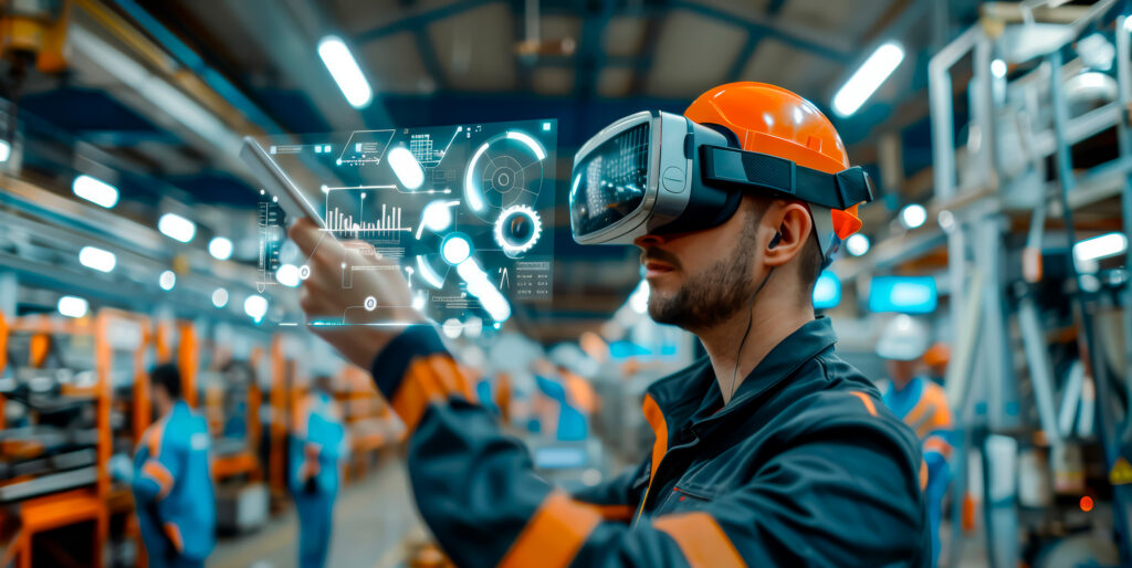 Pracovník v oranžovej prilbe a VR okuliaroch ovláda digitálny holografický rozhranie v priemyselnej hale.