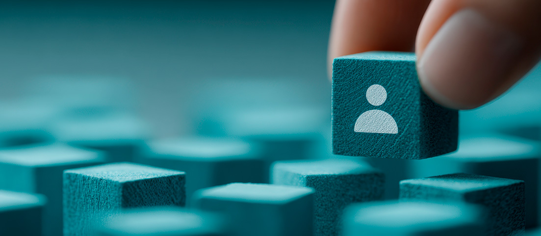 Ruka vyberá modrý kockový blok s ikonou osoby spomedzi viacerých podobných blokov.