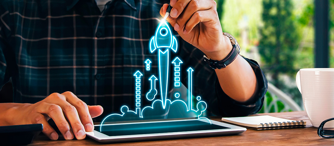 Ruka kresliaca digitálnu raketu štartujúcu z tabletu, symbolizujúca rast a rozvoj startupu.